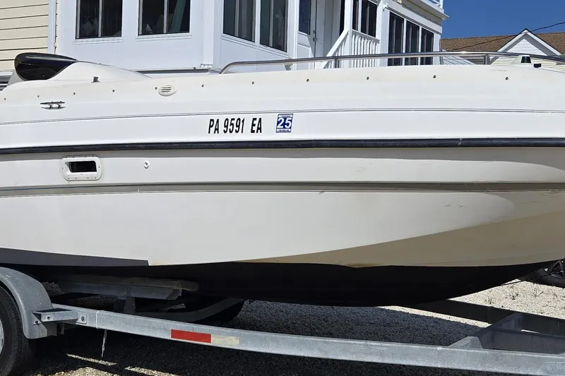 Slide: The Image of 1999 Bayliner 2459 Rendezvous DX/LX boat on trailer, parked near a house. - 3