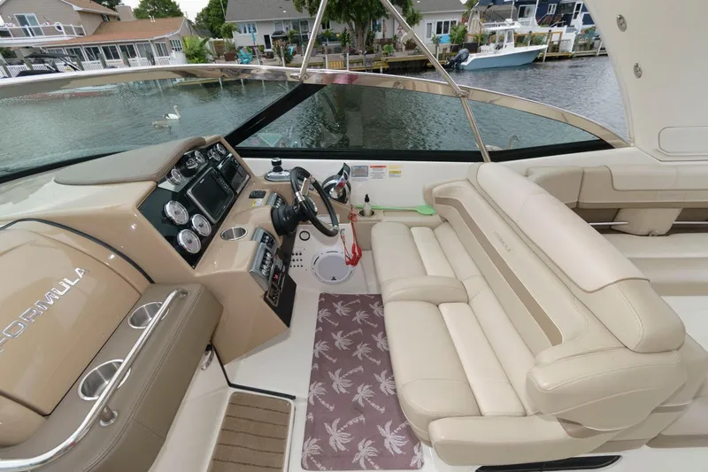 Slide: The Image of 2014 Formula 350 Crossover Bowrider interior with beige seating and control panel, dockside view. - 6