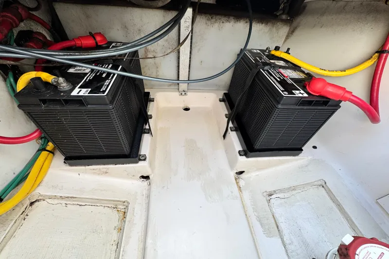 Slide: The Image of 2015 Pursuit DC 265 Dual Console boat battery compartment with dual batteries and wiring. - 16