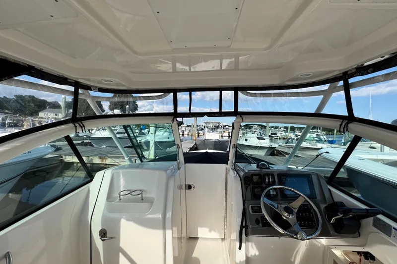 Slide: The Image of 2015 Pursuit DC 265 Dual Console boat interior with steering wheel and dashboard at marina. - 19