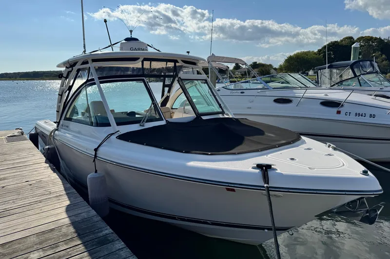 Slide: The Image of 2015 Pursuit DC 265 Dual Console boat docked on a sunny day. - 2