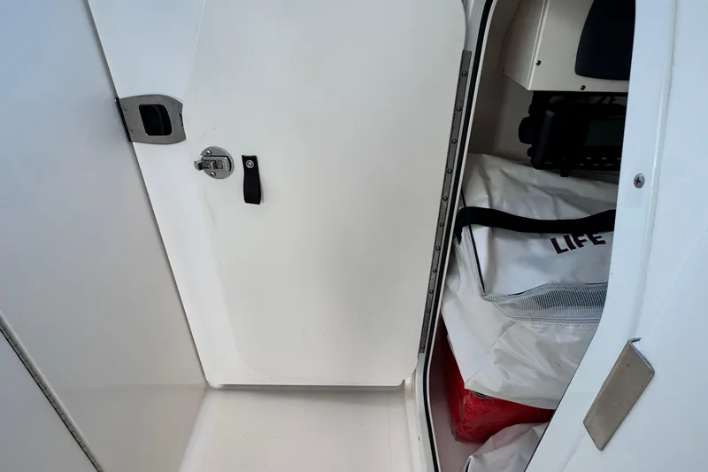Slide: The Image of 2015 Pursuit DC 265 Dual Console storage compartment with life jackets. - 28