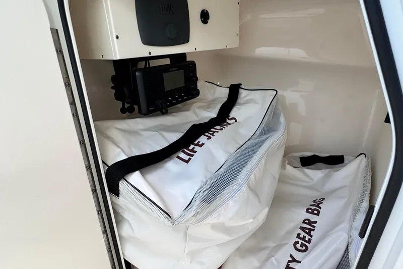 Slide: The Image of Storage compartment in a 2015 Pursuit DC 265 Dual Console with life jackets and safety gear bags. - 29