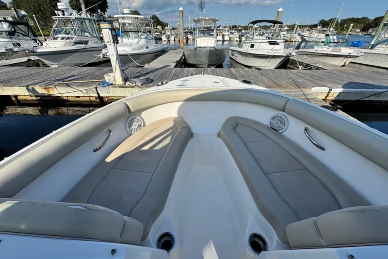 Slide: The Image of 2015 Pursuit DC 265 Dual Console boat interior at marina, featuring cushioned seating. - 41