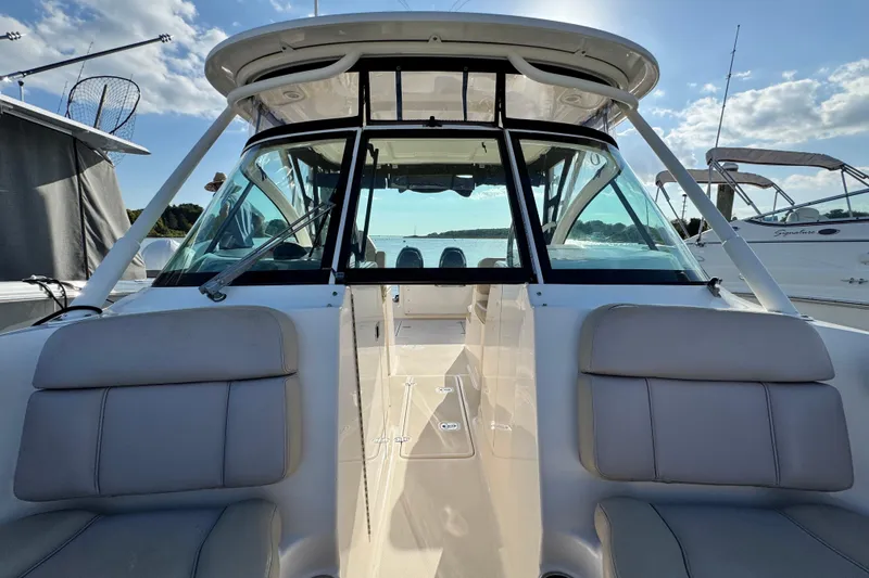 Slide: The Image of 2015 Pursuit DC 265 Dual Console boat interior with seating and windshield, docked under a sunny sky. - 47