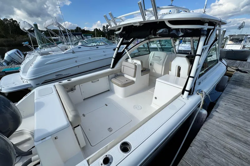 Slide: The Image of 2015 Pursuit DC 265 Dual Console boat docked, showcasing spacious seating and sleek design. - 8