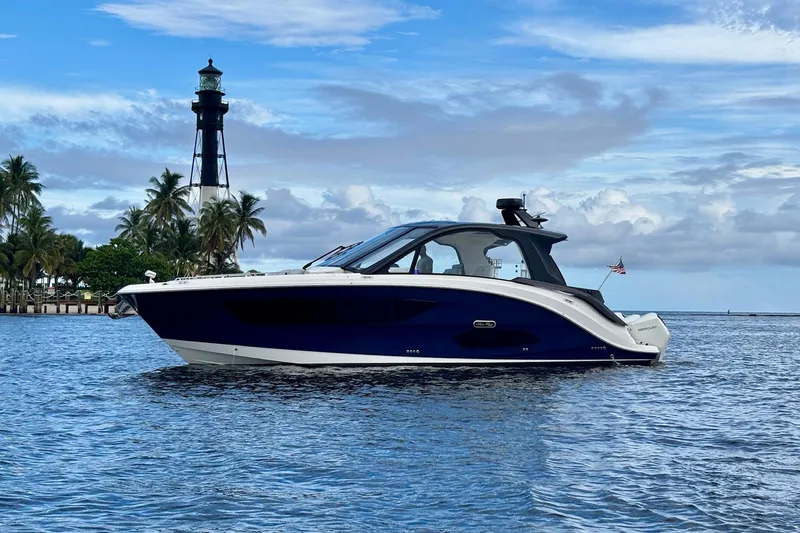 Slide: The Image of 2022 Sea Ray Sundancer 370 Outboard cruising near a lighthouse with palm trees. - 1