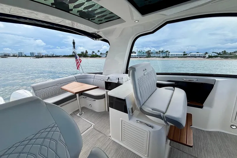 Slide: The Image of 2022 Sea Ray Sundancer 370 Outboard interior with seating, table, and scenic water view. - 13