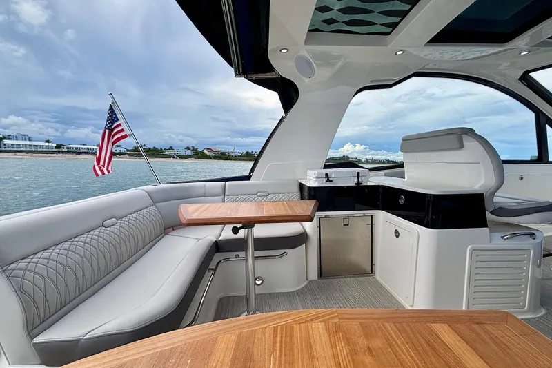 Slide: The Image of 2022 Sea Ray Sundancer 370 Outboard interior with seating, table, and American flag. - 14