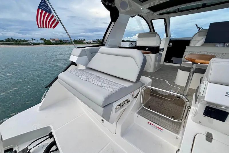 Slide: The Image of 2022 Sea Ray Sundancer 370 Outboard interior with seating, table, and American flag. - 28