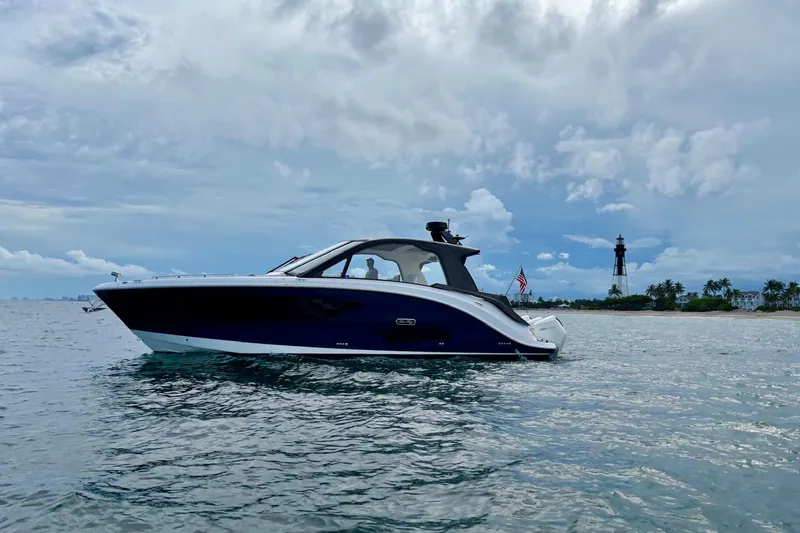 Slide: The Image of 2022 Sea Ray Sundancer 370 Outboard cruising near a lighthouse on a cloudy day. - 36