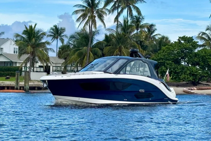 Slide: The Image of 2022 Sea Ray Sundancer 370 Outboard cruising near palm-lined shore. - 4