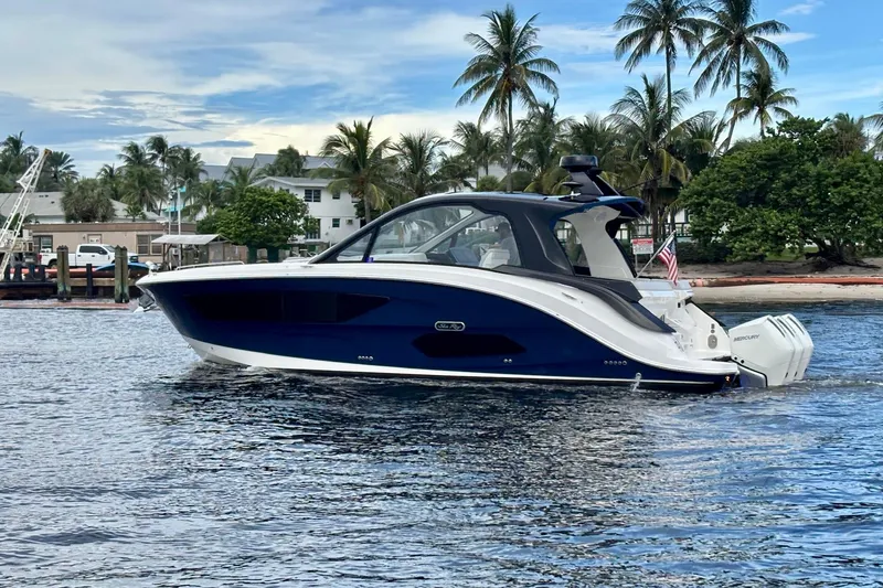 Slide: The Image of 2022 Sea Ray Sundancer 370 Outboard cruising on water with palm trees in background. - 5