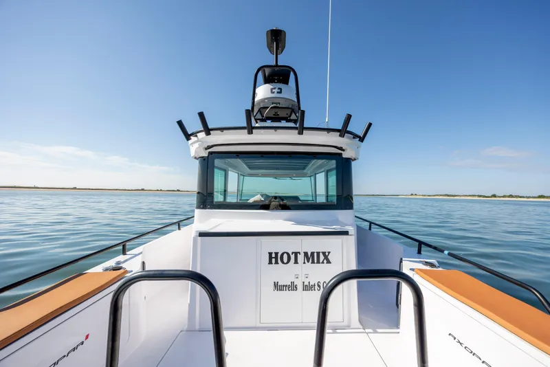 Slide: The Image of 2024 Axopar 28 CABIN boat on calm water, clear sky background. - 11