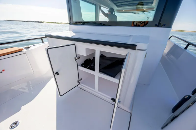 Slide: The Image of 2024 Axopar 28 CABIN boat with open storage compartment on deck. - 16