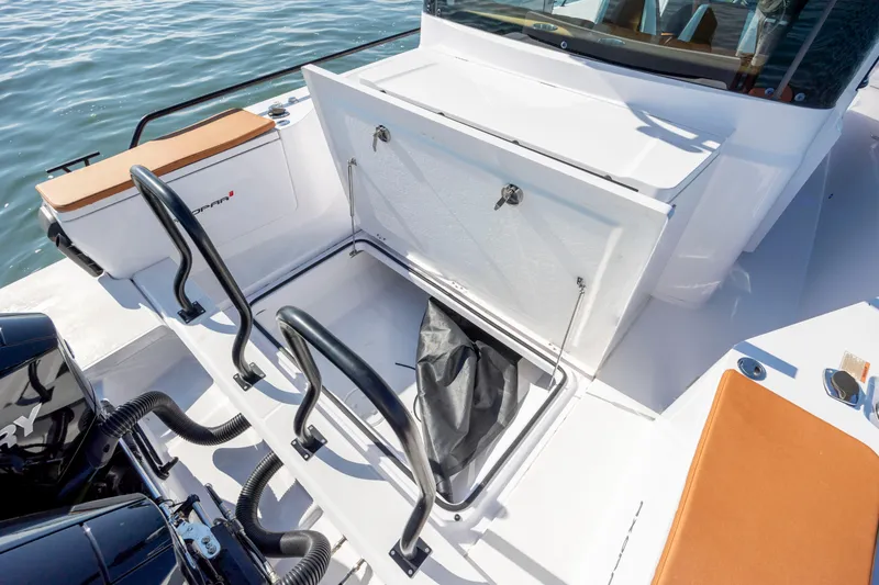 Slide: The Image of 2024 Axopar 28 CABIN boat with open storage compartment on deck. - 19