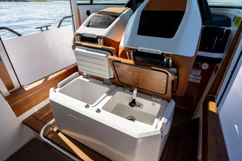 Slide: The Image of 2024 Axopar 28 CABIN interior with open storage compartments and sink. - 28