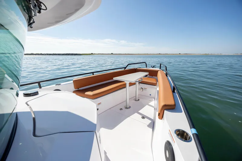 Slide: The Image of 2024 Axopar 28 CABIN boat with seating area and table on calm water. - 29