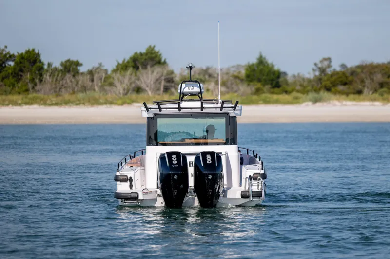 Slide: The Image of 2024 Axopar 28 CABIN boat with dual engines on a serene waterway. - 3