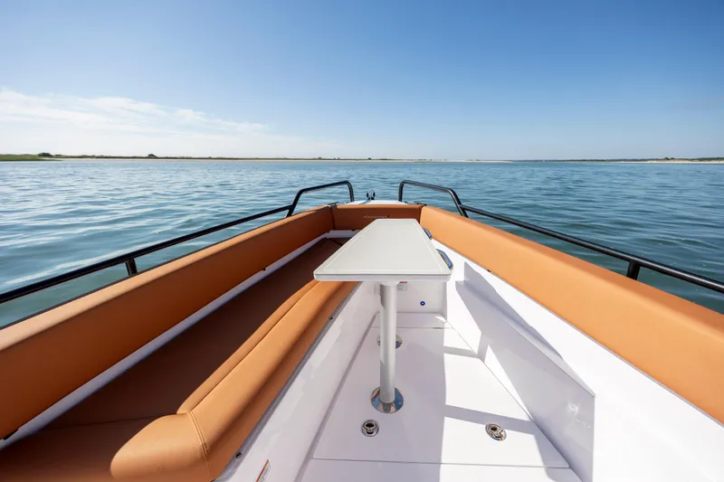 Slide: The Image of 2024 Axopar 28 CABIN boat with tan seating and table on calm water. - 30