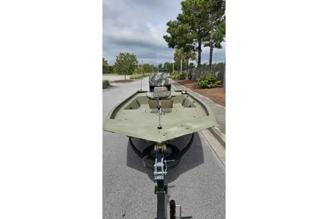Slide: The Image of 2019 Tracker Grizzly 1860 CC boat on trailer, parked on a road with trees. - 2