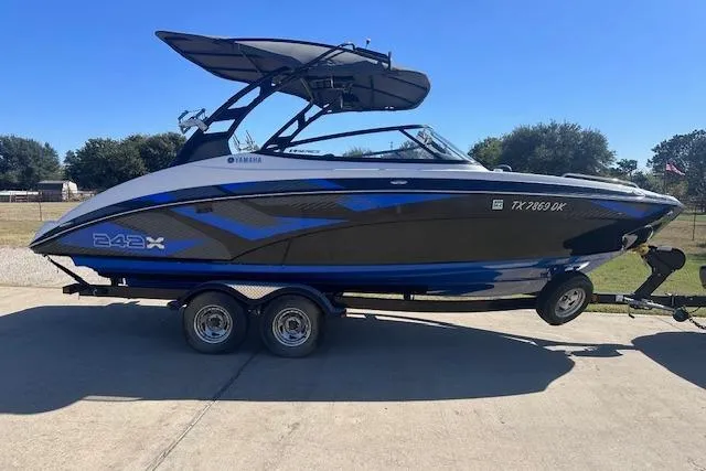 The Image of 2016 Yamaha Boats 242X E-Series on trailer, sleek design, blue and black color scheme. - 0
