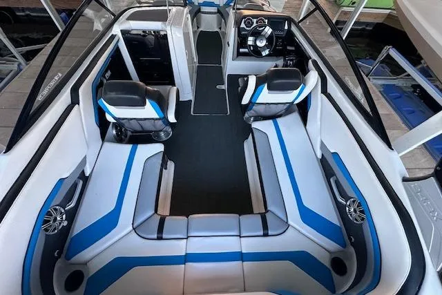 Slide: The Image of 2016 Yamaha Boats 242X E-Series interior with blue and white seating, docked in marina. - 15