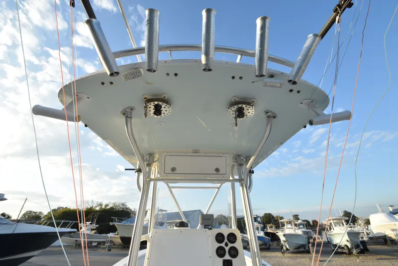 Slide: The Image of 2005 Regulator 24 Forward Seating boat with rod holders and control panel, docked under blue sky. - 16