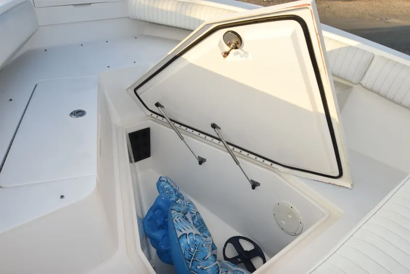 Slide: The Image of 2005 Regulator 24 Forward Seating boat storage compartment with open hatch and blue life jacket. - 25