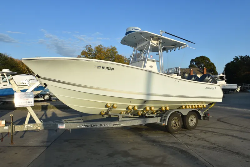 Slide: The Image of 2005 Regulator 24 Forward Seating boat on trailer, parked outdoors under clear sky. - 4