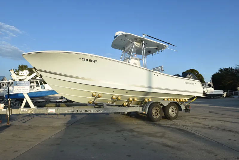 Slide: The Image of 2005 Regulator 24 Forward Seating boat on trailer, parked outdoors under clear sky. - 5