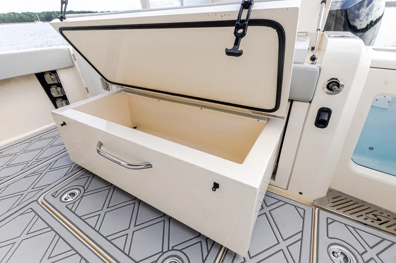 Slide: The Image of 2024 Scout 377 LXF boat storage compartment with open lid on deck. - 20