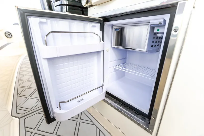 Slide: The Image of Open mini fridge inside 2024 Scout 377 LXF boat, showcasing interior storage space. - 23