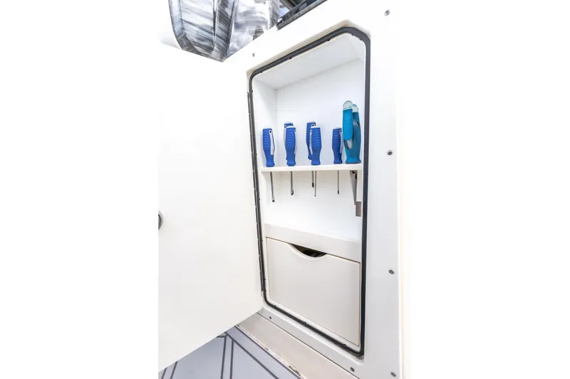 Slide: The Image of 2024 Scout 377 LXF boat tool storage compartment with organized blue-handled tools. - 24