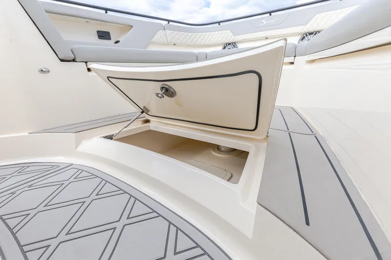 Slide: The Image of 2024 Scout 377 LXF boat storage compartment with open hatch and cushioned seating. - 58