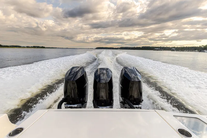 Slide: The Image of 2024 Scout 377 LXF boat with triple engines cruising on a scenic waterway. - 68