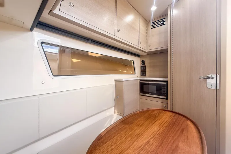 Slide: The Image of 2024 Scout 377 LXF interior with modern cabinetry, microwave, and wooden table. - 79