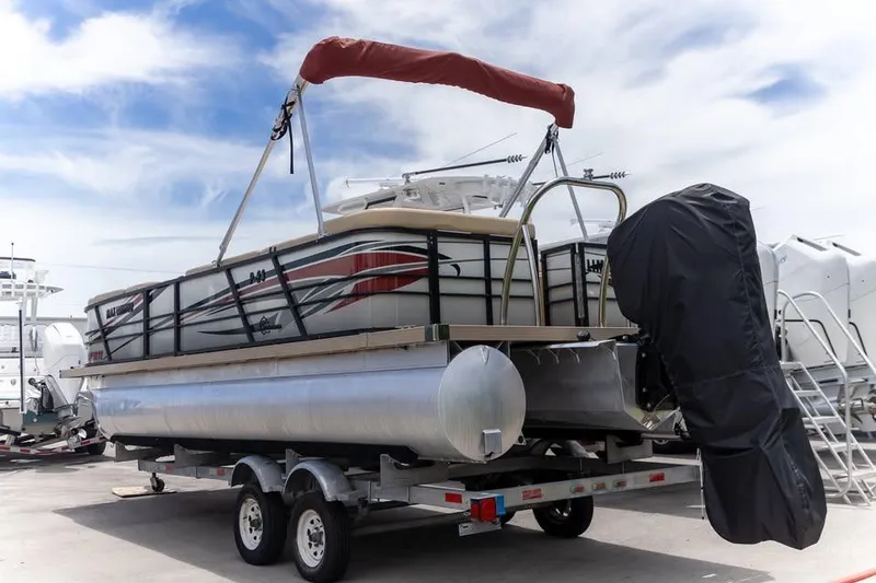 Slide: The Image of 2022 Massimo Marine P-23 MAX Limited pontoon boat on trailer, under blue sky. - 2