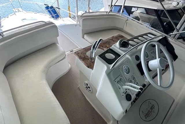 Slide: The Image of 1994 Mainship 40 Sedan Bridge helm with seating, featuring a sleek control panel and waterfront view. - 16