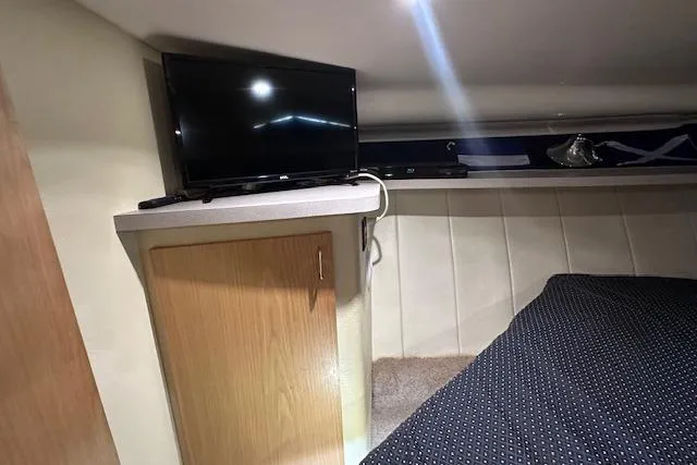 Slide: The Image of 1994 Mainship 40 Sedan Bridge cabin with TV, wooden cabinet, and cozy bedding. - 25