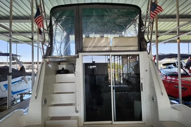 Slide: The Image of 1994 Mainship 40 Sedan Bridge yacht docked, featuring rear view with stairs and sliding glass door. - 3