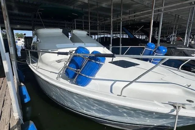 Slide: The Image of 1994 Mainship 40 Sedan Bridge docked, featuring a sleek white exterior and blue fenders. - 8