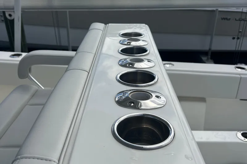 Slide: The Image of 2015 SeaVee 39Z boat interior with seating and storage, docked near lush greenery. - 47