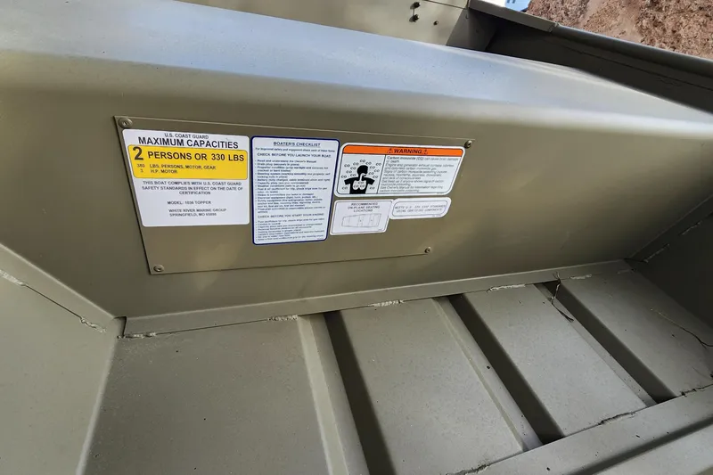 Slide: The Image of 2026 Tracker Grizzly 10 Jon boat capacity and safety labels, maximum 2 persons or 330 lbs. - 2