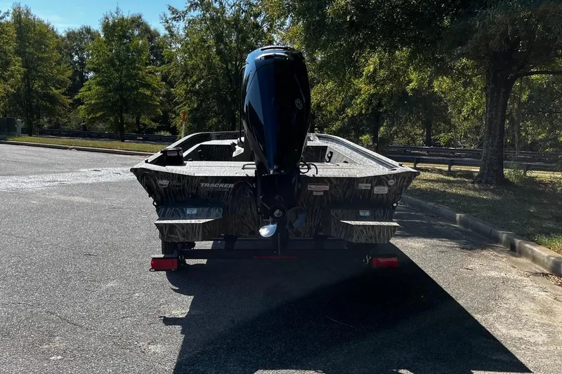 Slide: The Image of 2026 Tracker Grizzly 1860 CC boat on trailer, parked outdoors, surrounded by trees. - 4