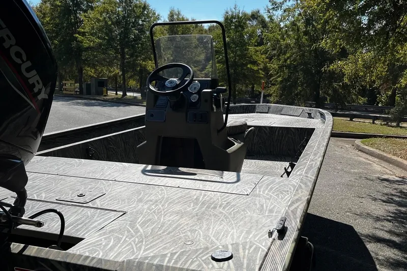 Slide: The Image of 2026 Tracker Grizzly 1860 CC boat with Mercury engine, parked outdoors on a sunny day. - 5
