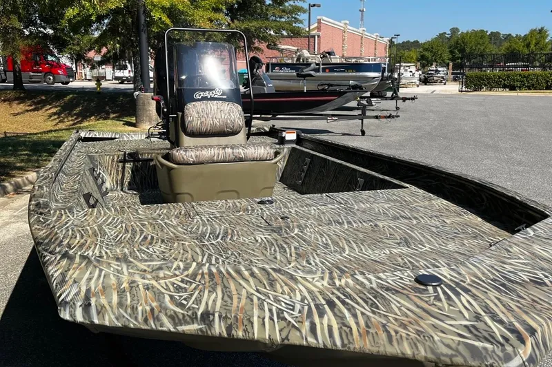Slide: The Image of 2026 Tracker Grizzly 1860 CC boat with camouflage design in a parking lot. - 7