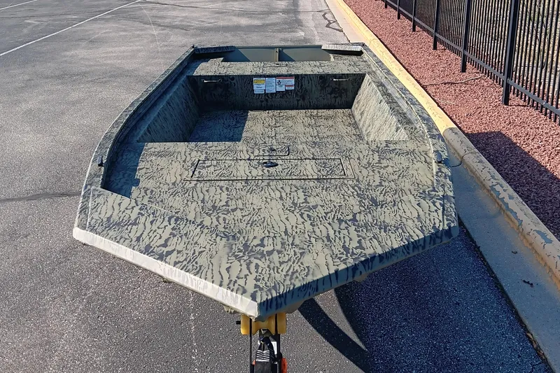 Slide: The Image of 2026 Tracker Grizzly 1648 Utility boat with camouflage design on pavement. - 2