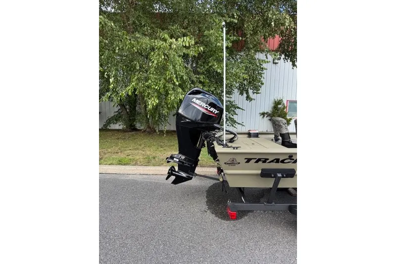 Slide: The Image of 2026 Tracker Grizzly 1754 SC boat with Mercury outboard motor, parked outdoors. - 2