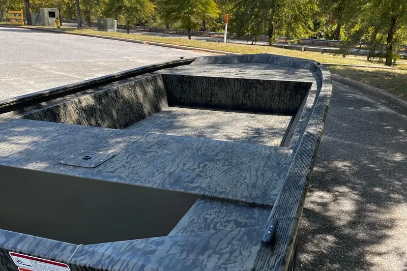 Slide: The Image of 2026 Tracker Grizzly 1648 Utility boat with camouflage design in a parking area. - 5